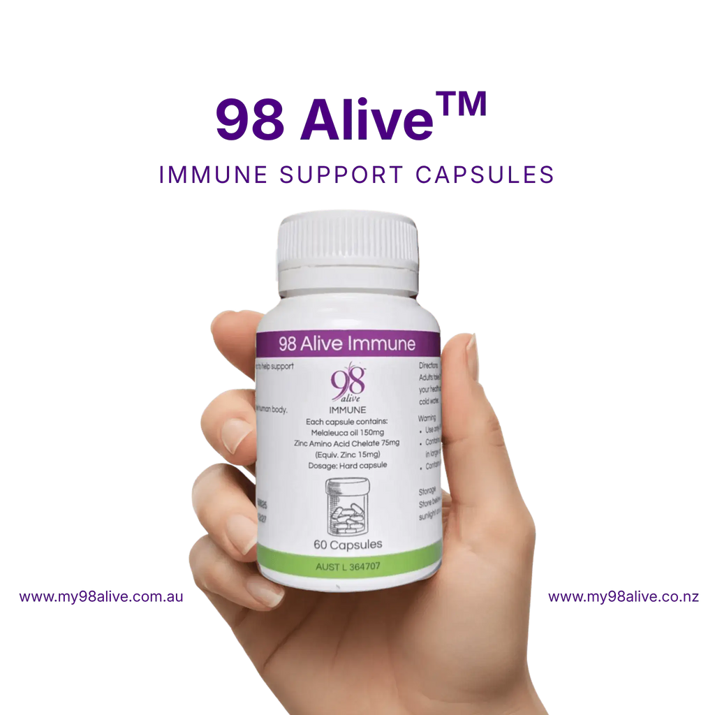 Hand holding a bottle of 98 Alive immune support capsules against a white background